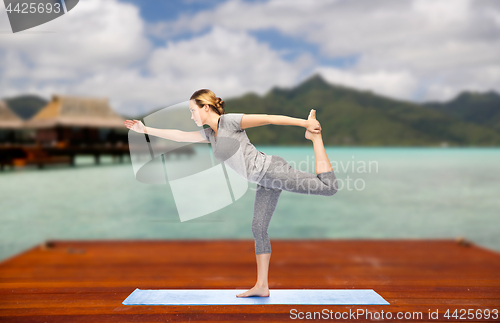 Image of woman making yoga lord of the dance pose outdoor