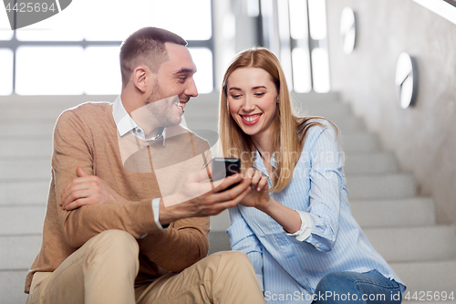 Image of man and woman with smartphone at office stairs