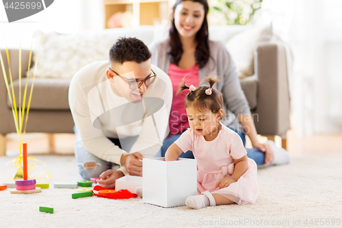 Image of baby girl with birthday gift and parents at home 