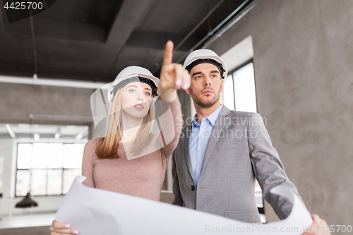 Image of architects with blueprint and helmets at office