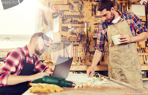 Image of carpenters with laptop and blueprint at workshop