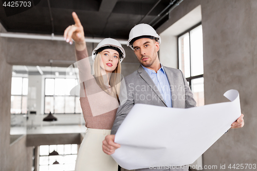 Image of architects with blueprint and helmets at office