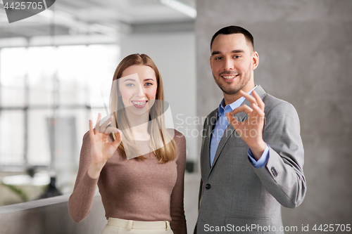 Image of businesswoman and businessman showing ok at office