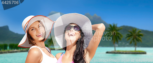 Image of smiling young women in hats on bora bora beach