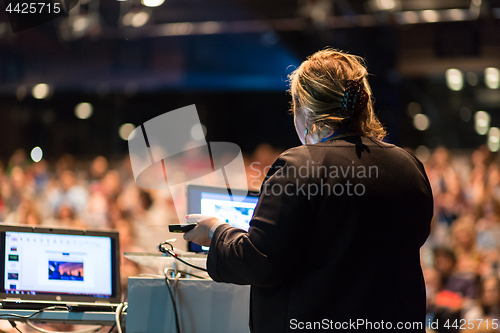 Image of Female public speaker giving talk at Business Event.