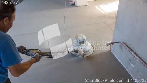 Image of Laborer polishing sand and cement screed floor.