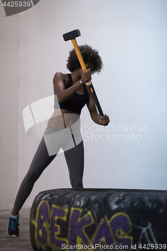 Image of black woman workout with hammer and tractor tire