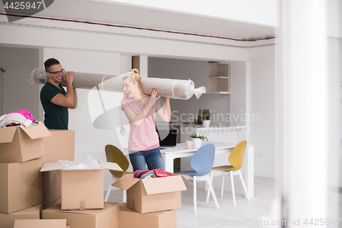 Image of couple carrying a carpet moving in to new home