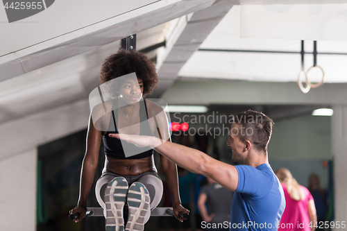 Image of black woman doing parallel bars Exercise with trainer