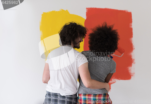 Image of multiethnic couple painting interior wall