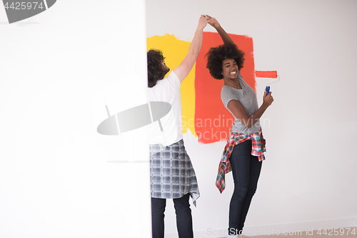 Image of multiethnic couple painting interior wall