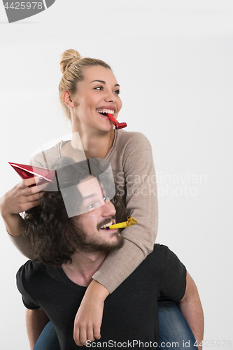 Image of couple in party hats blowing in whistle