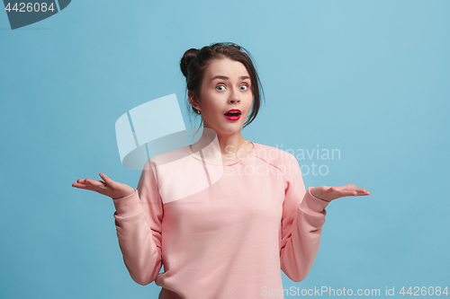 Image of Portrait of dissatisfied young woman over blue. Beautiful woman looking suprised