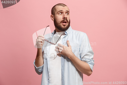 Image of Let me think. Doubtful pensive man with thoughtful expression making choice against pink background