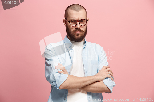 Image of The serious business man standing and looking at camera against pink background.