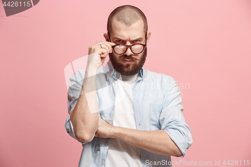 Image of Suspiciont. Doubtful man with thoughtful expression making choice against pink background