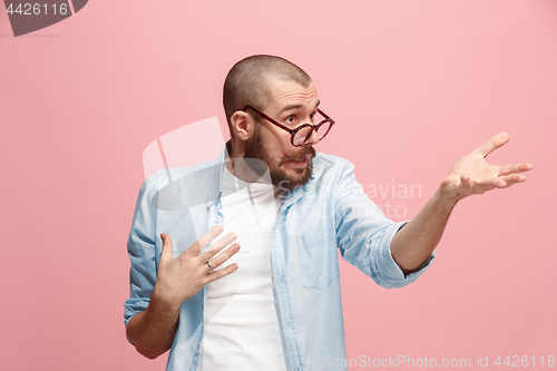 Image of Beautiful male half-length portrait isolated on pink studio backgroud. The young emotional surprised man