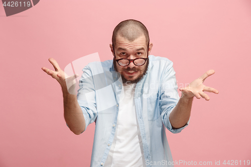 Image of Beautiful male half-length portrait isolated on pink studio backgroud. The young emotional surprised man