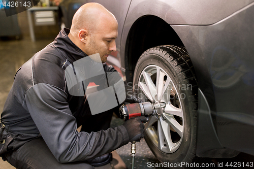 Image of auto mechanic with screwdriver changing car tire