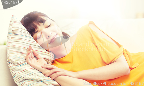 Image of happy asian teenage girl sleeping on sofa at home