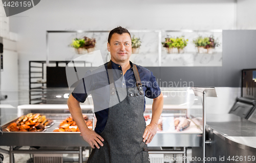 Image of male seller with seafood at fish shop fridge