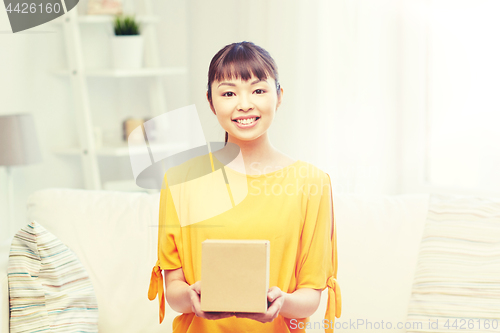 Image of happy asian young woman with parcel box at home