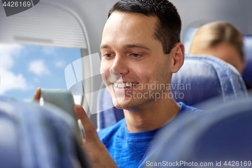 Image of happy man sitting in plane with smartphone