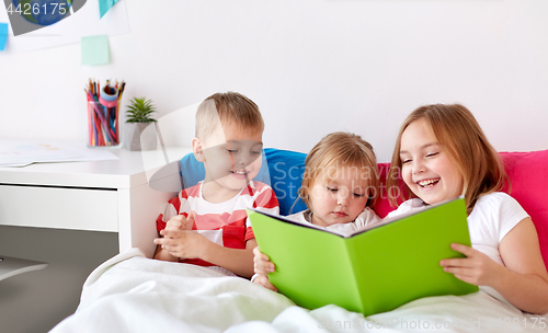 Image of little kids reading book in bed at home