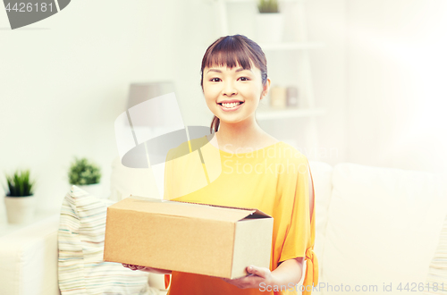 Image of happy asian young woman with parcel box at home