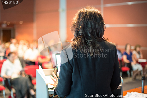 Image of Female public speaker giving talk at Business Event.