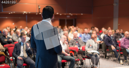 Image of Public speaker giving talk at business event.