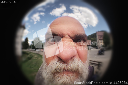 Image of an angry man looking to a peephole door