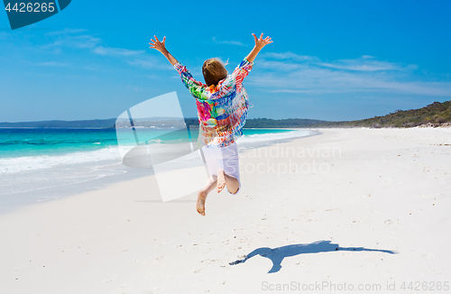 Image of Summertime woman jump for joy beach