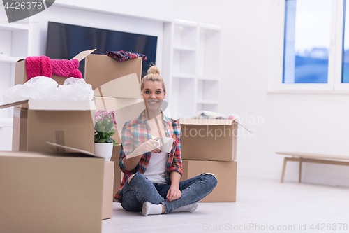 Image of woman with many cardboard boxes sitting on floor