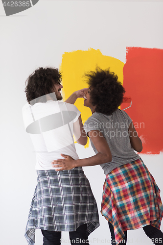 Image of multiethnic couple painting interior wall