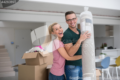 Image of couple carrying a carpet moving in to new home