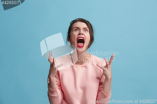 Image of The young emotional angry woman screaming on blue studio background