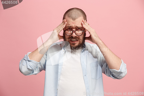 Image of Man having headache. Isolated over pink background.