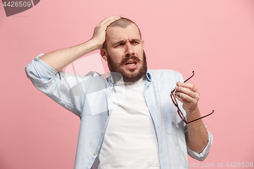 Image of Man having headache. Isolated over pink background.