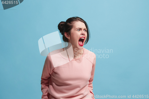 Image of The young emotional angry woman screaming on blue studio background