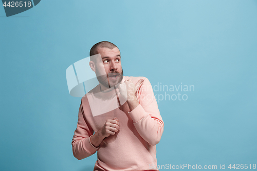 Image of The young man whispering a secret behind her hand over blue background