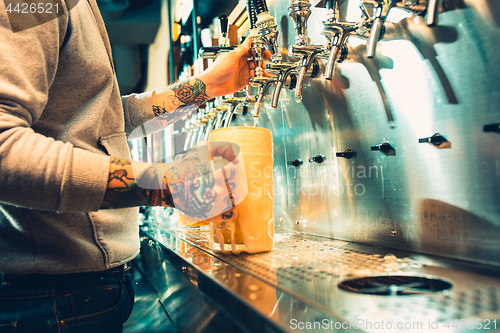 Image of Hand of bartender pouring a large lager beer in tap.