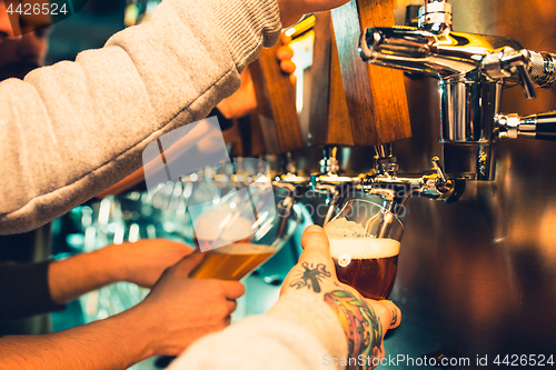 Image of Hand of bartender pouring a large lager beer in tap.