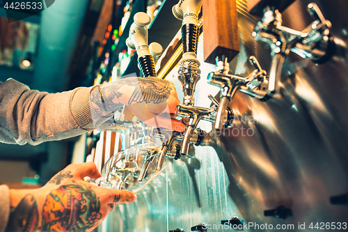 Image of Hand of bartender pouring a large lager beer in tap.