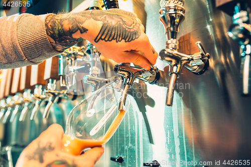 Image of Hand of bartender pouring a large lager beer in tap.