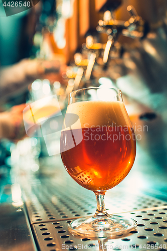 Image of Hand of bartender pouring a large lager beer in tap.