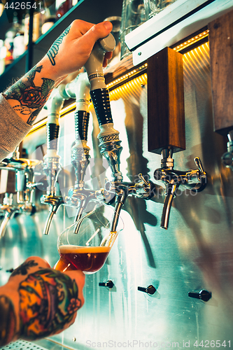 Image of Hand of bartender pouring a large lager beer in tap.