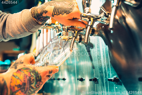 Image of Hand of bartender pouring a large lager beer in tap.