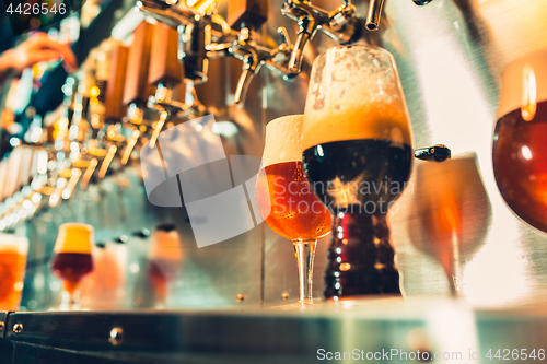 Image of Hand of bartender pouring a large lager beer in tap.