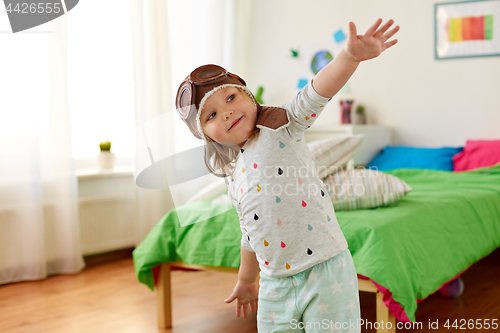 Image of happy little girl in pilot hat playing at home